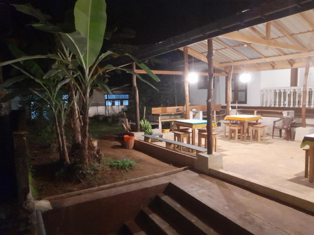 a patio with tables and chairs and a palm tree at New Born Restaurant & Accommodation in Hikkaduwa