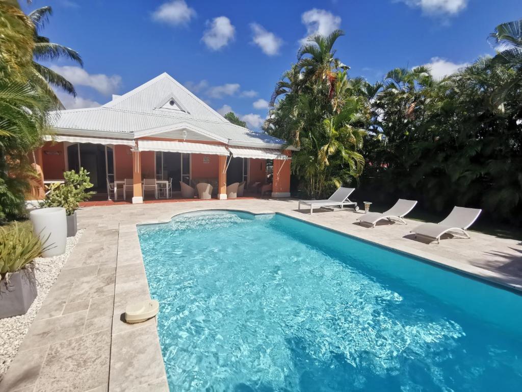サン・フランソワにあるVilla Alizée charmante villa avec piscineの椅子2脚と家のあるプール