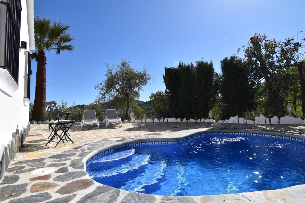 einen Pool im Garten mit Stühlen und einem Tisch in der Unterkunft Finca El Corinto -The Enchanted Place in Cómpeta