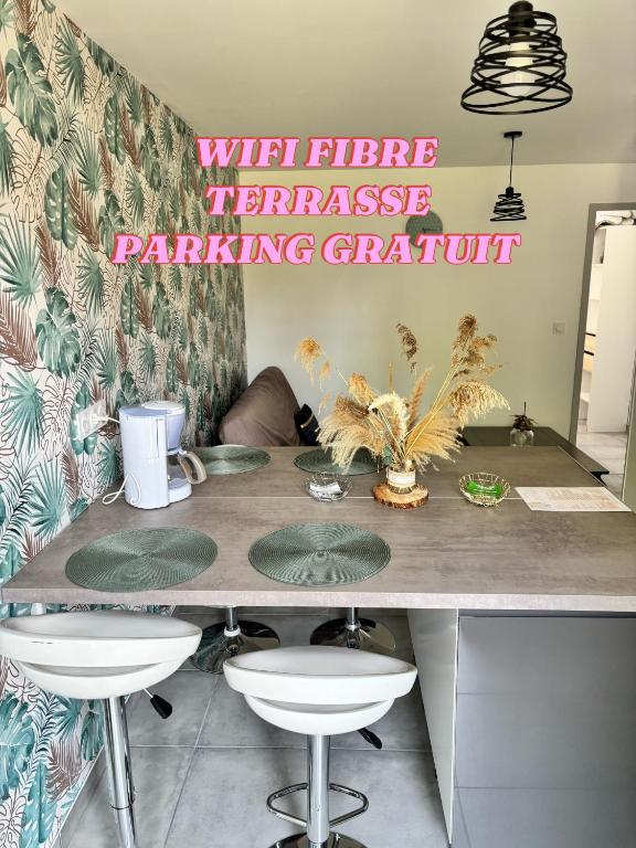 une cuisine avec un grand comptoir avec des tabourets et un panneau rose dans l'établissement Au Champ Fleuri, à Bracieux