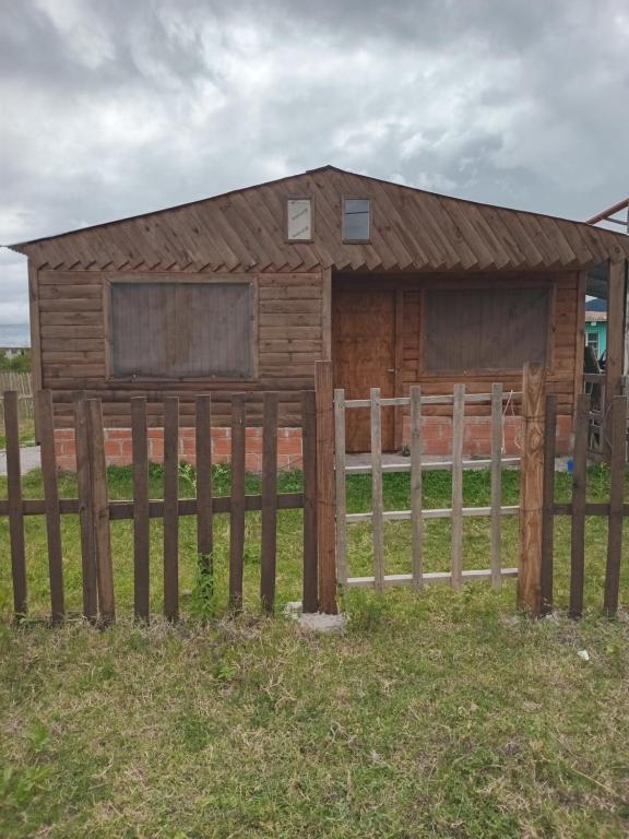 een houten hut met een hek in een veld bij Cabaña Anita in Cerrillos