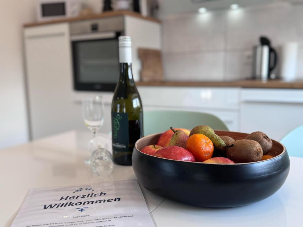a bowl of fruit on a counter with a bottle of wine at Ferienwohnung Dariana Schwalbach/Saar in Schwalbach