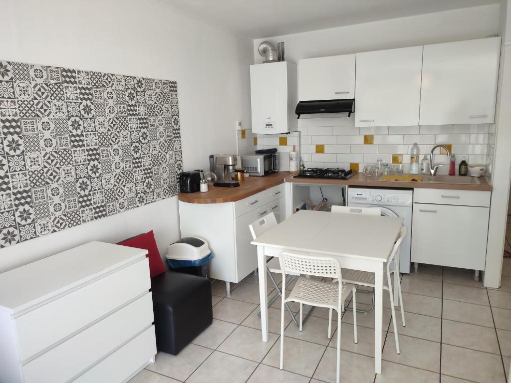 une cuisine avec des armoires blanches et une table et des chaises dans l'établissement Palavas studio vue mer, à Palavas-les-Flots