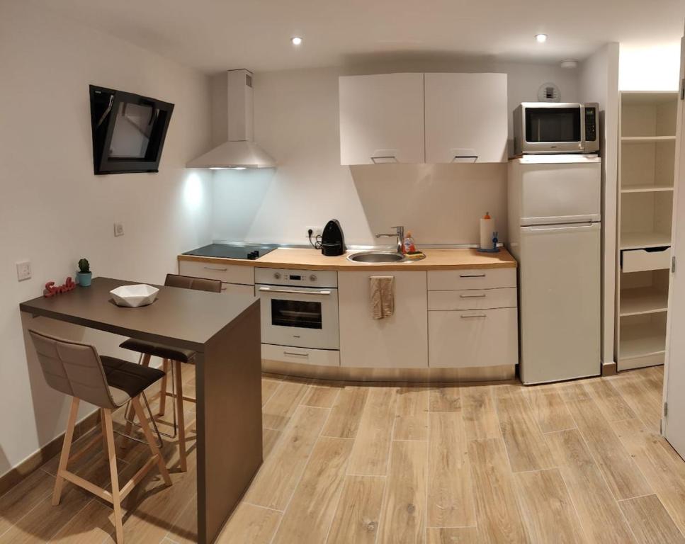 - une cuisine avec des placards blancs, une table et un réfrigérateur dans l'établissement Mouans Sartoux studio with pool access, à Mouans-Sartoux