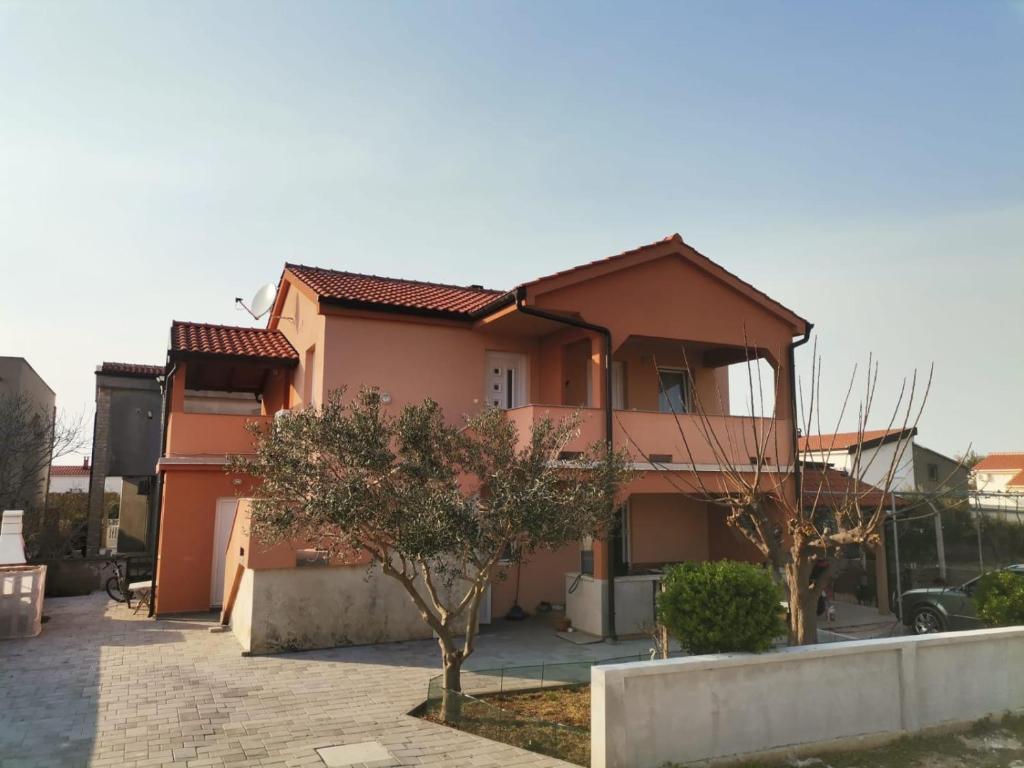 a pink house with trees in front of it at Apartmani Martinović in Vir