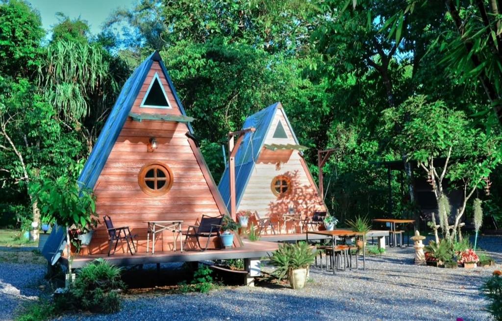 a small cabin with a blue roof and tables and chairs at Pingjai Halal Camping in Ban Nong Mai Kaen