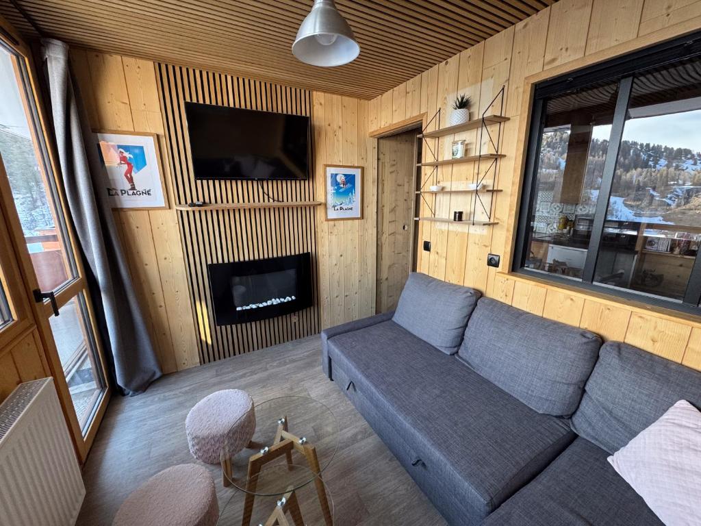 un salon avec un canapé et une cheminée dans l'établissement Magnifique appartement 4-6 personnes au pied des pistes à La Plagne Centre, à La Plagne Tarentaise