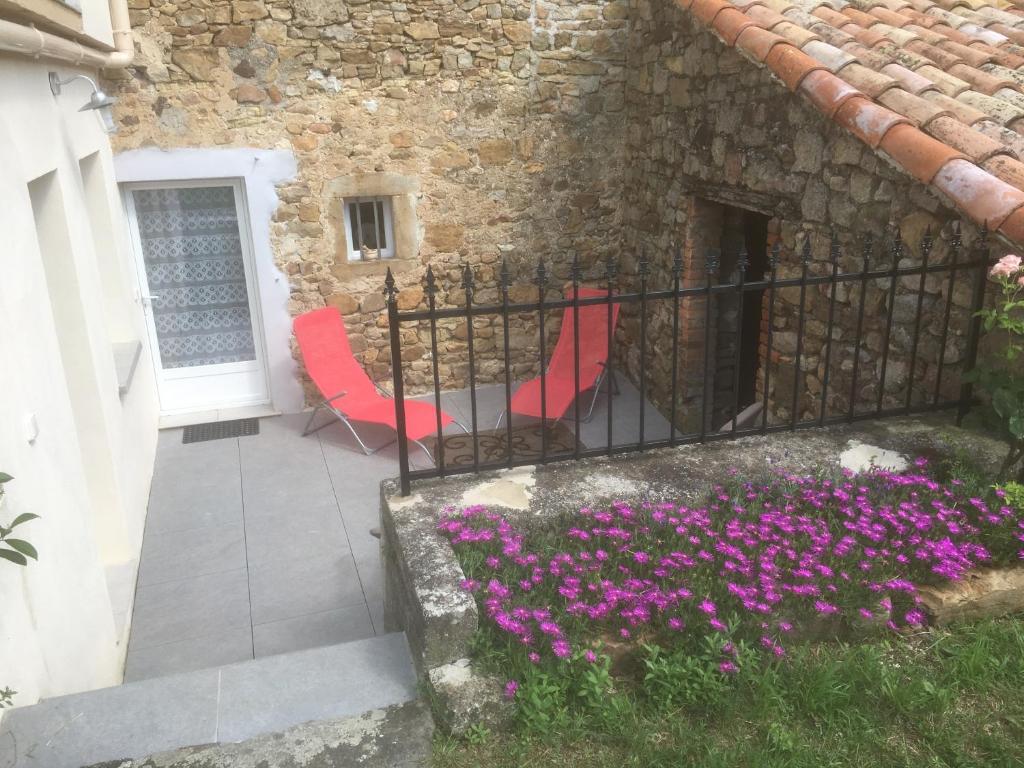 une terrasse avec des chaises rouges et des fleurs violettes dans l'établissement Magnanerie Leony 2, à Saint-Florent-sur-Auzonnet
