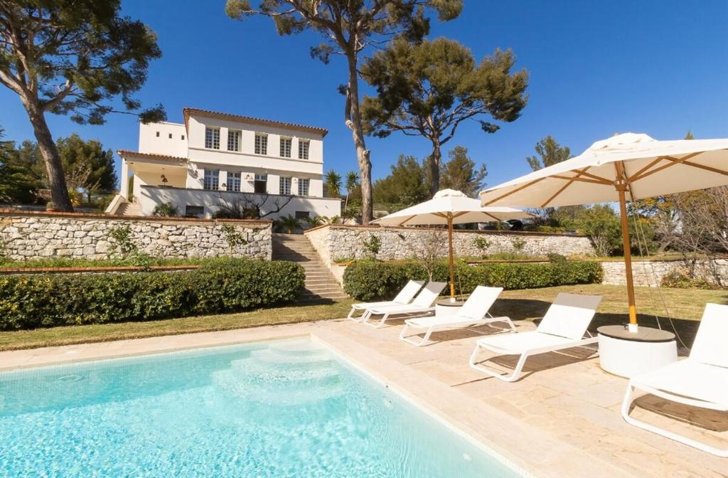 une piscine avec des chaises et des parasols ainsi qu'une maison dans l'établissement La Roca Blanca, à Cassis