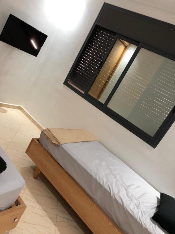 ein Zimmer mit einem Bett mit einem großen Fenster in der Unterkunft Appartement cosy 1er étage in Kenitra