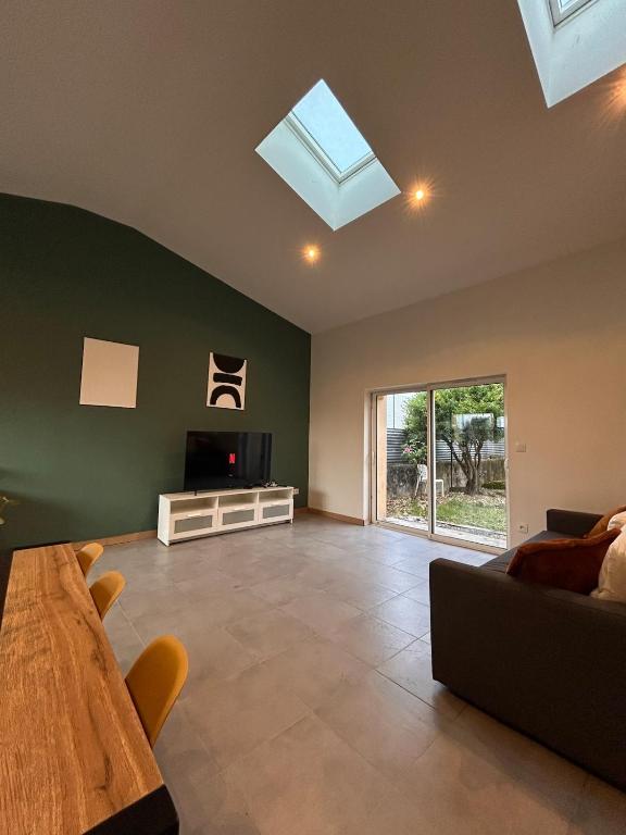 a living room with a couch and a tv and a table at Spacious house - garden, Netflix & shops in Béguey