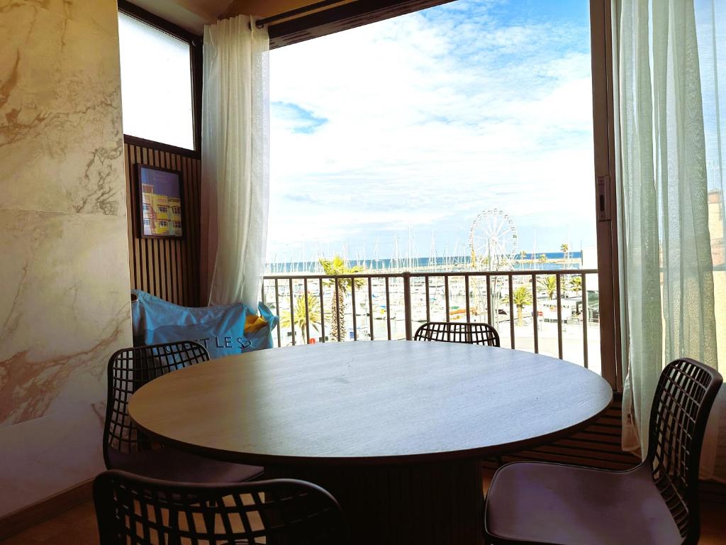 une table et des chaises dans une pièce avec une grande fenêtre dans l'établissement Grand studio neuf vue magnifique, à Canet