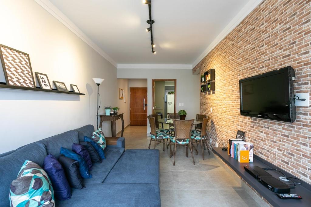 圣保罗Apartamento grande, espaçoso - Mackenzie, Higienópolis的客厅设有蓝色的沙发和砖墙