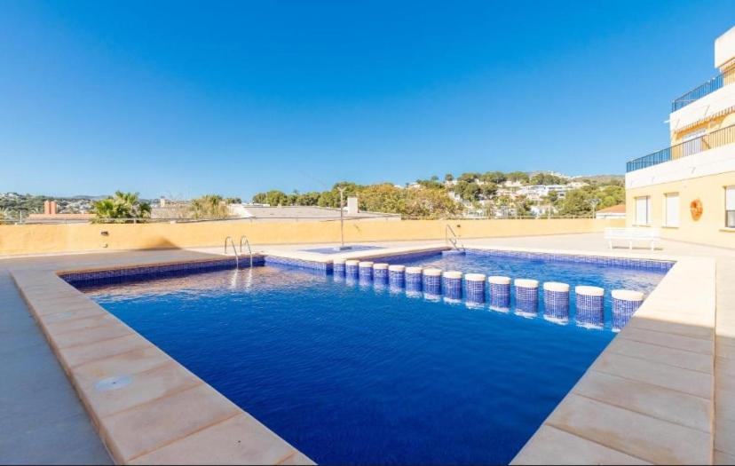 a swimming pool with blue water in front of a building at Apartamento en Moraira Centro con Piscina in Moraira