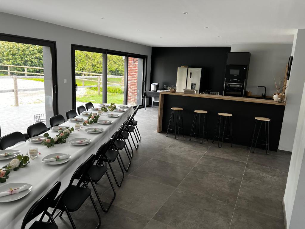 une longue salle à manger avec une longue table et des chaises dans l'établissement Maison au cœur de la forêt, à Râches