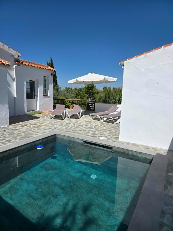 a swimming pool in front of a house at CASA AGUILAR in Cómpeta