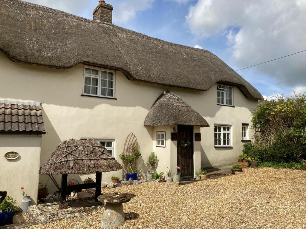a large white house with a thatched roof at Guest Suite at 31 Little England in Milborne Saint Andrew