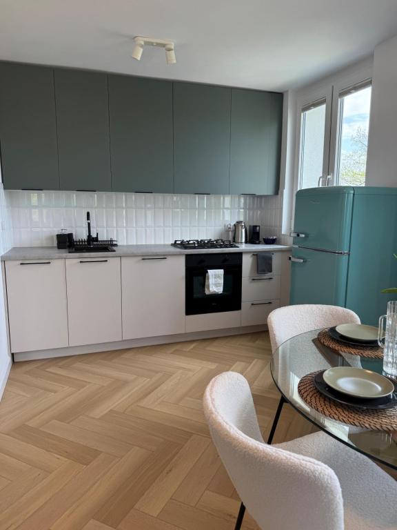 a kitchen with white cabinets and a table with chairs at Studio 77 - nowoczesny apartament w Otwocku in Otwock