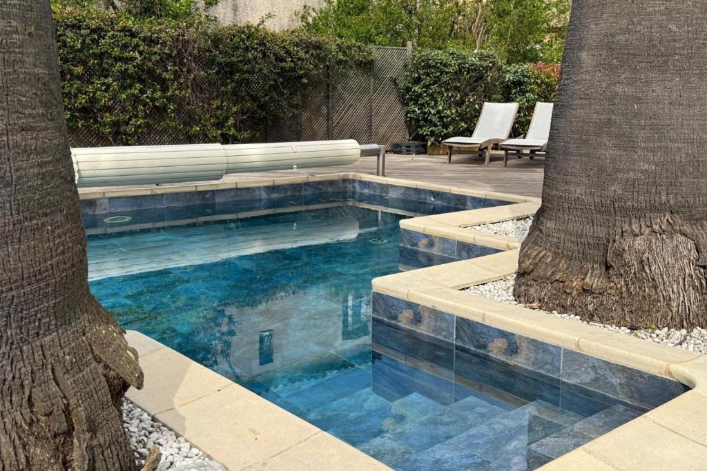 - une piscine entourée de deux palmiers dans une cour dans l'établissement Villa Yoléa avec piscine privée au Grau du Roi Vacances de rêve, au Grau-du-Roi