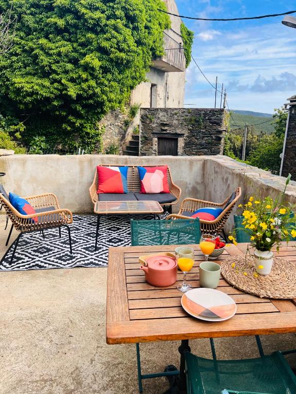 un patio avec une table, des chaises et un canapé dans l'établissement Très jolie maison aux portes du Cap Corse, à Sisco