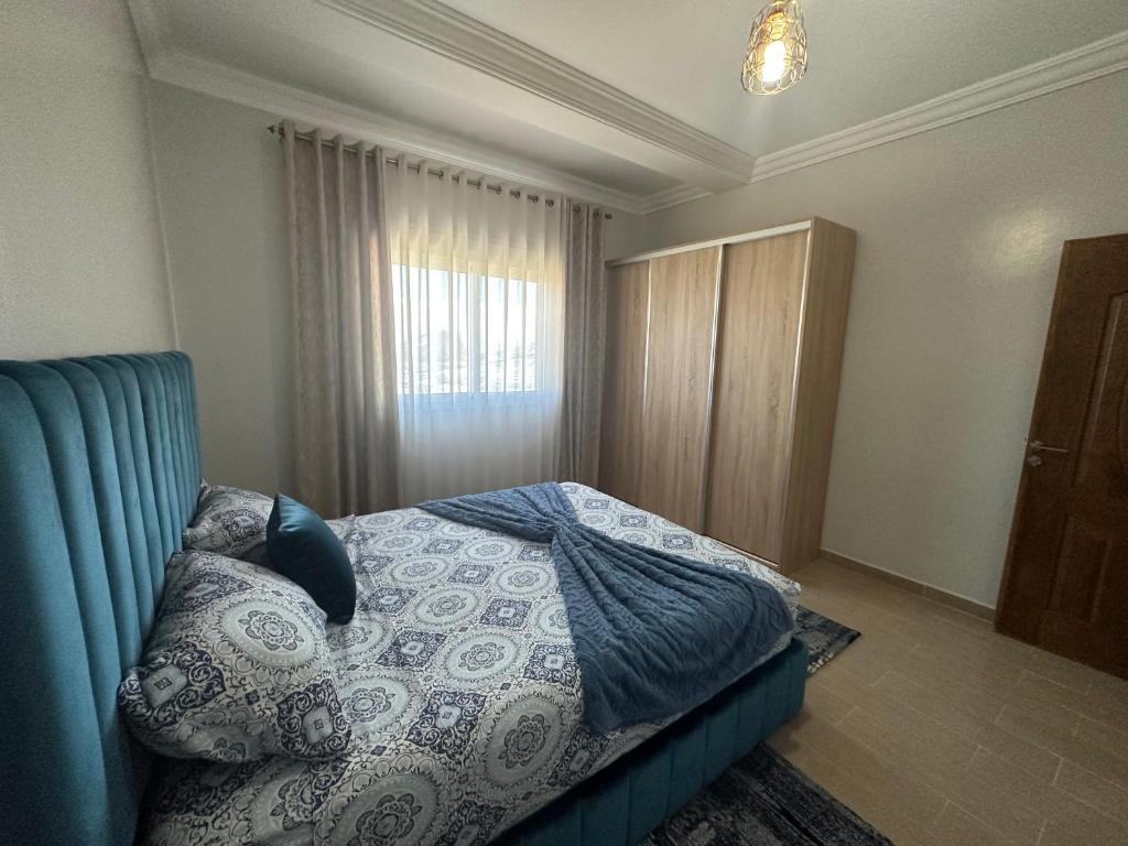 a bedroom with a bed with a blue couch and a window at Appartement à Houma, proche Port Tanger Med in Dalia
