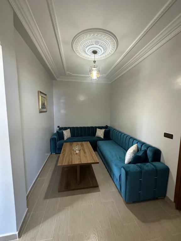 a living room with a blue couch and a wooden table at Appartement à Houma, proche Port Tanger Med in Dalia