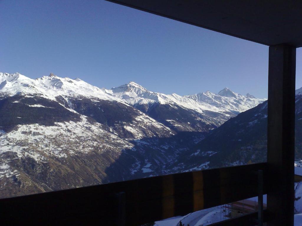 una ventana con vistas a una cordillera nevada en Immeuble Mont Noble, en Les Collons