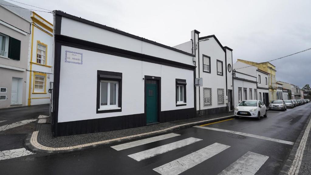 a white building with a green door on a street at Casa do Negrão in Ponta Delgada