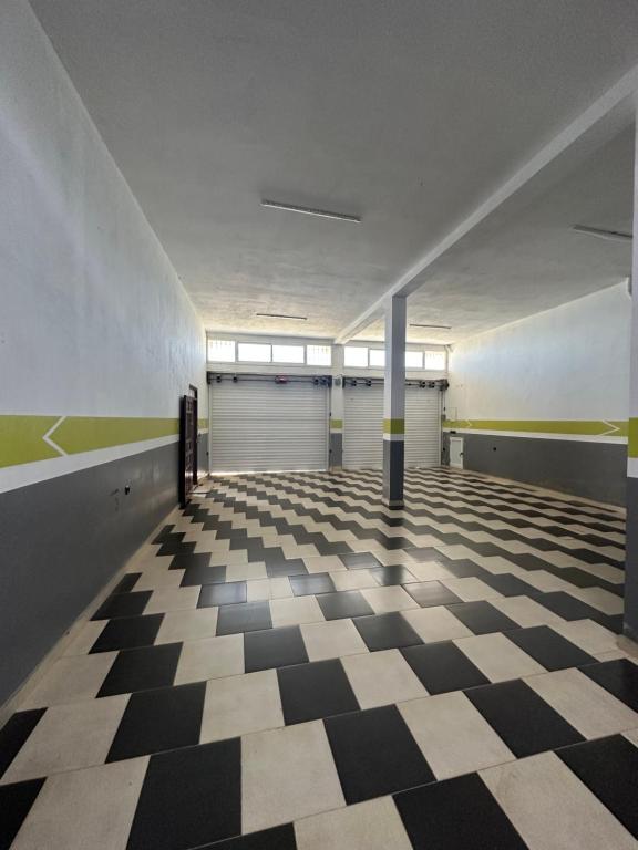 a room with a checkered floor and two garage doors at Appartement à Houma, proche Port Tanger Med in Dalia