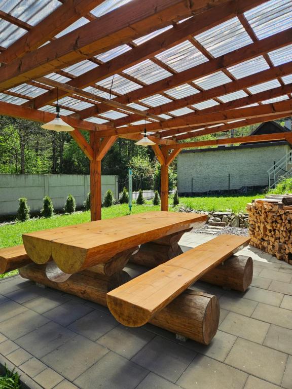 a wooden picnic table and benches under a pavilion at Ubytovanie Hronec in Hronec