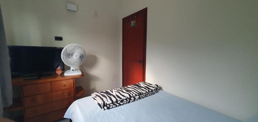 a bedroom with a bed with a fan and a television at quarto duplo in Caraguatatuba