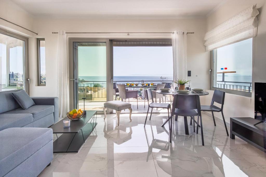 a living room with a couch and a table with chairs at Era Suites Lagonisi in Kalívia Thorikoú