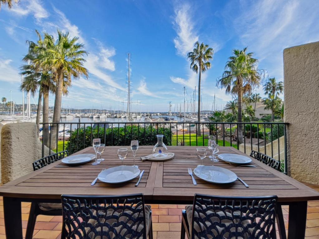 une table en bois avec des assiettes et des verres sur un balcon avec des palmiers dans l'établissement La Brigantine- Golfe de St Tropez, à Cogolin
