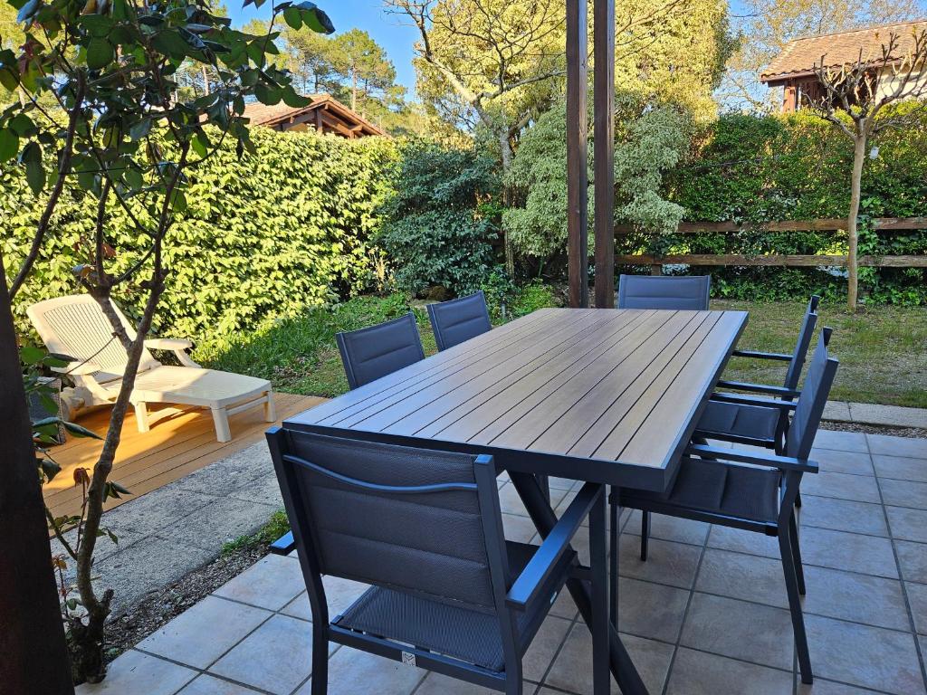 a wooden table and chairs on a patio at Maison abelias soustons plage in Soustons