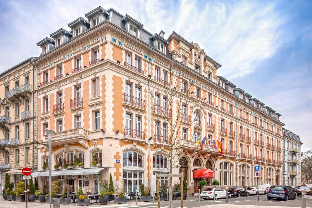 um grande edifício numa rua com carros estacionados na frente em Grand Hôtel Du Tonneau D'Or em Belfort