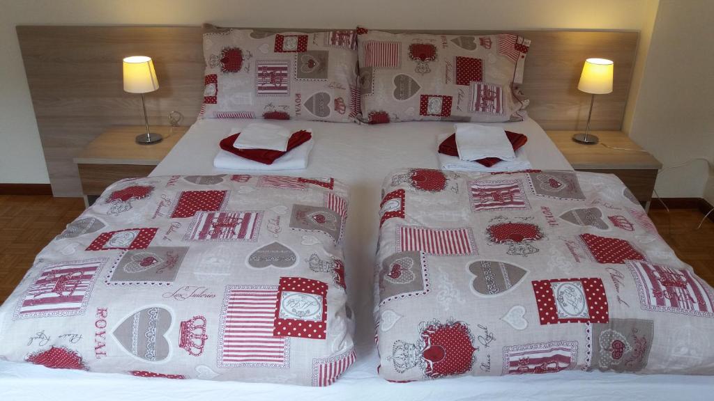two beds with red and white blankets and pillows at La Casa Di Fernanda in Belluno