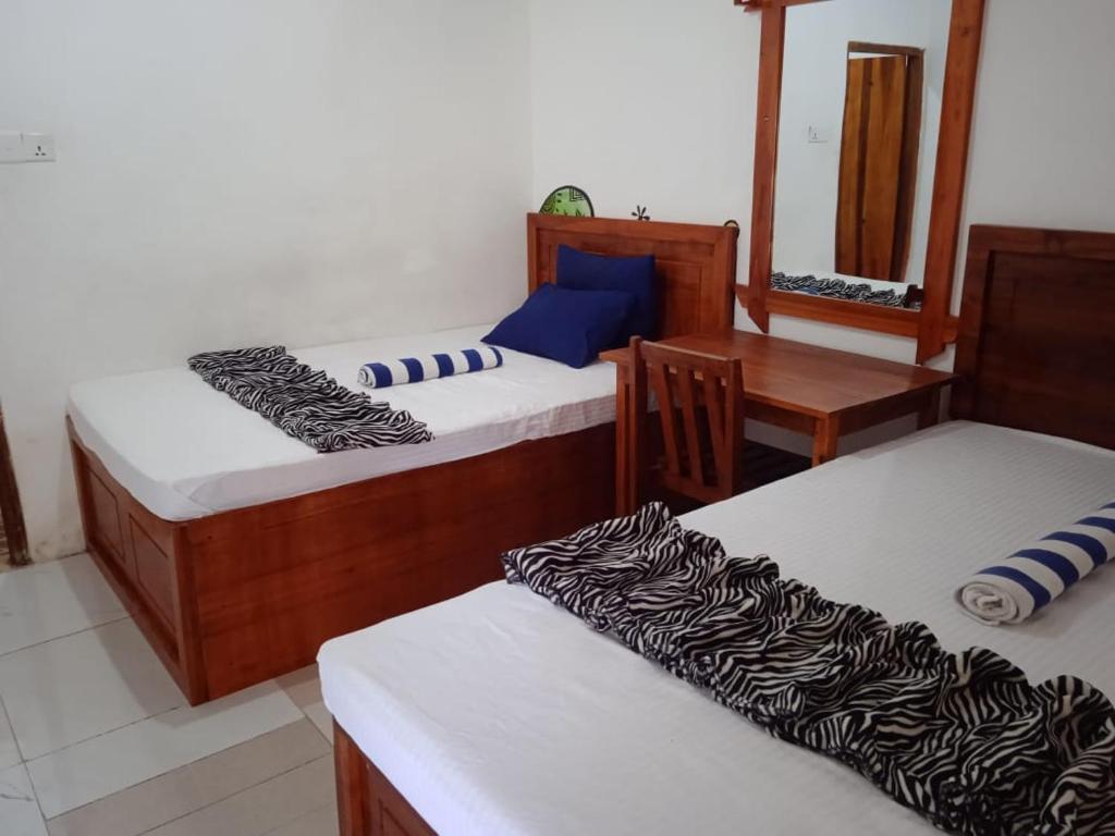 Habitación con 3 camas, mesa y espejo. en Ella Forest Bath, en Ella