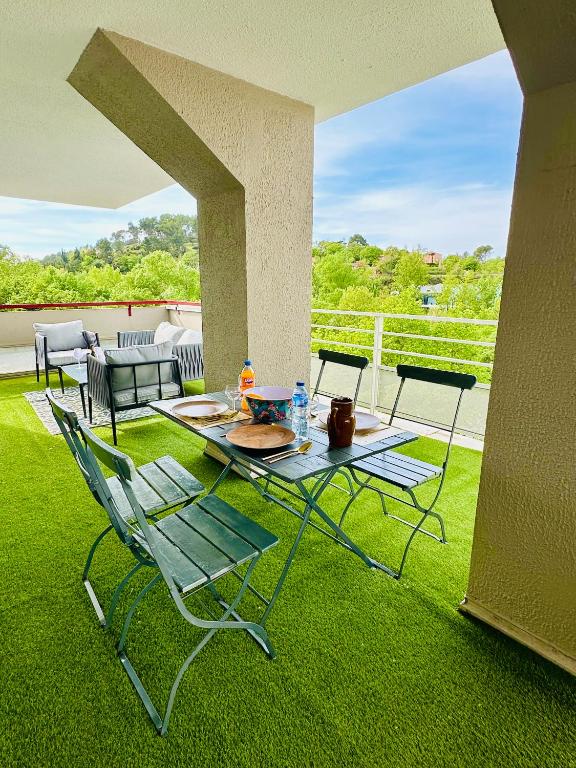 un patio avec une table et des chaises sur l'herbe dans l'établissement Le 409 Climatisé, Rooftop, Parking, à 10 min du centre ville d'Aix en Provence, à Aix-en-Provence