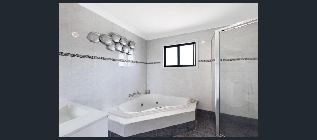 a bathroom with a tub and a sink and a shower at Long Jetty Beach House in Long Jetty