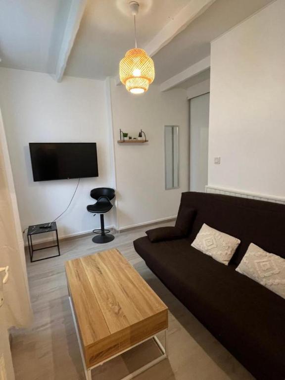 un salon avec un canapé noir et une table dans l'établissement T2 cozy en centre-ville, à Montélimar