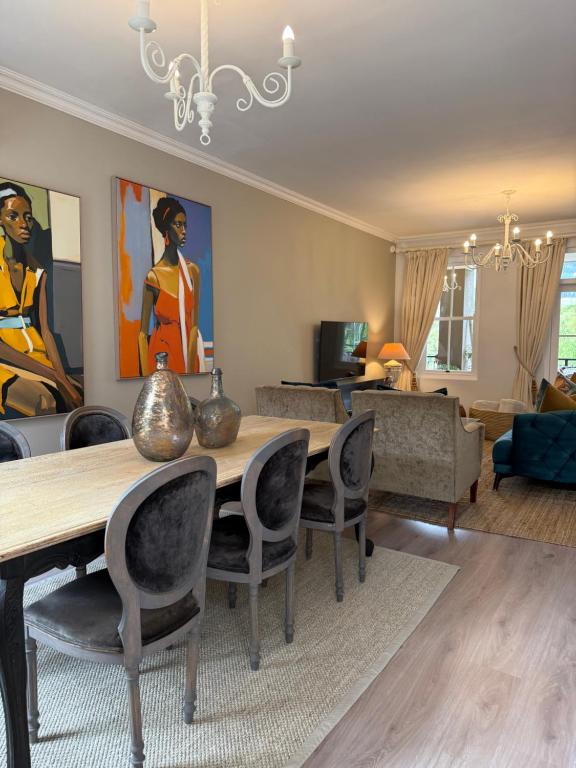 een woonkamer met een houten tafel en stoelen bij Franschoek Lermitage Villa 33 Three Bedroom Lake View in Franschhoek