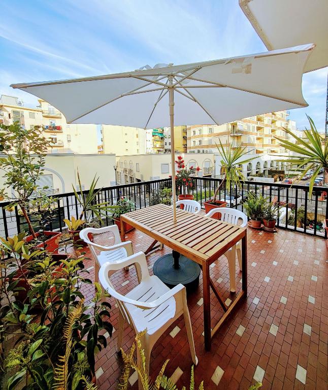 a wooden table and chairs with an umbrella on a balcony at Foce24 - City Garden - in Imperia