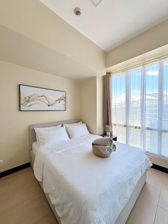 a bedroom with a white bed with a large window at Modern Condo in Mactan Newtown - OPR Tower B in Lapu Lapu City