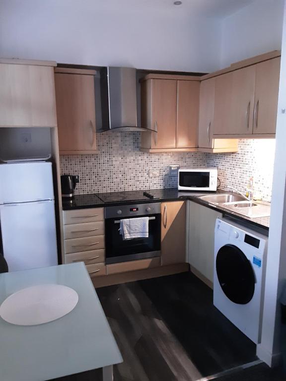 a kitchen with brown cabinets and a white appliance at Three bedroom apartment Darlington Victoria Road in Darlington