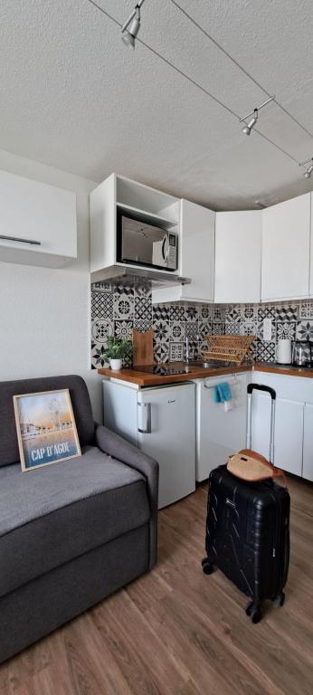 un salon avec un canapé et une cuisine dans l'établissement superbe studio avec piscine, ascenseur et accès direct sur le port, au Cap d'Agde