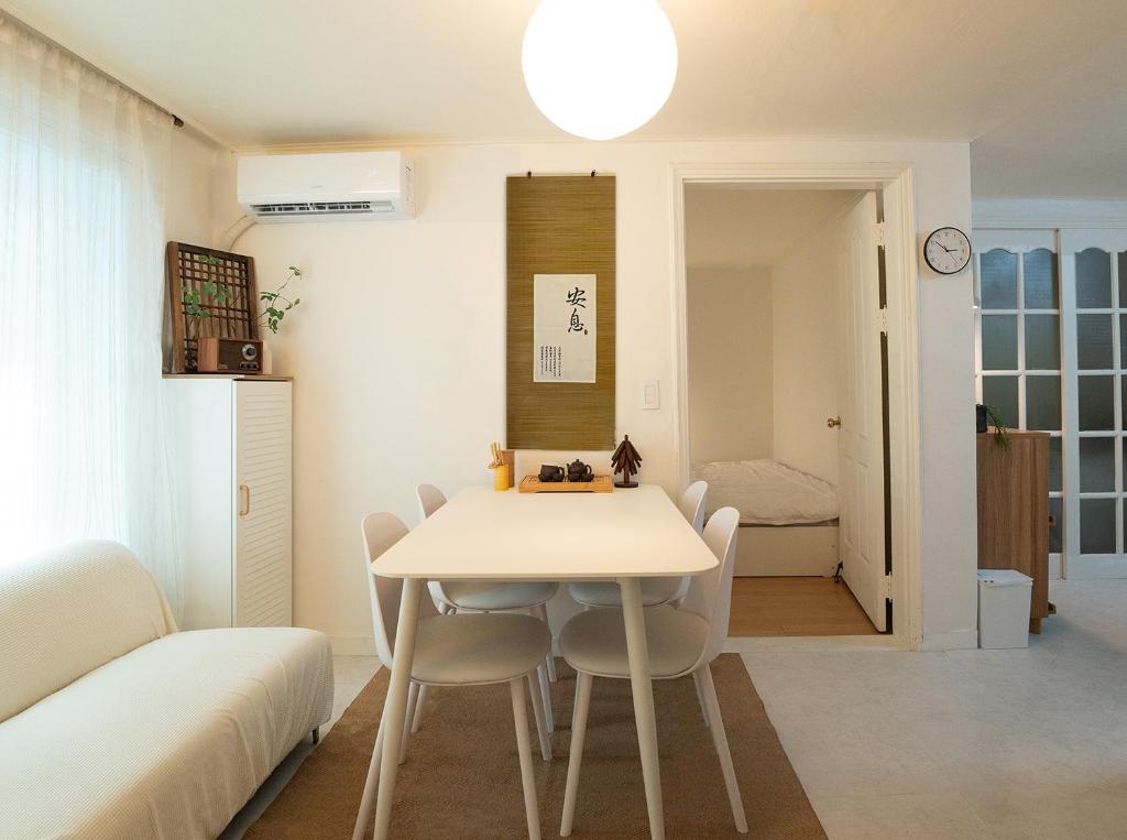 a white dining room with a table and chairs at Ahn-sik, 安息 in Seoul