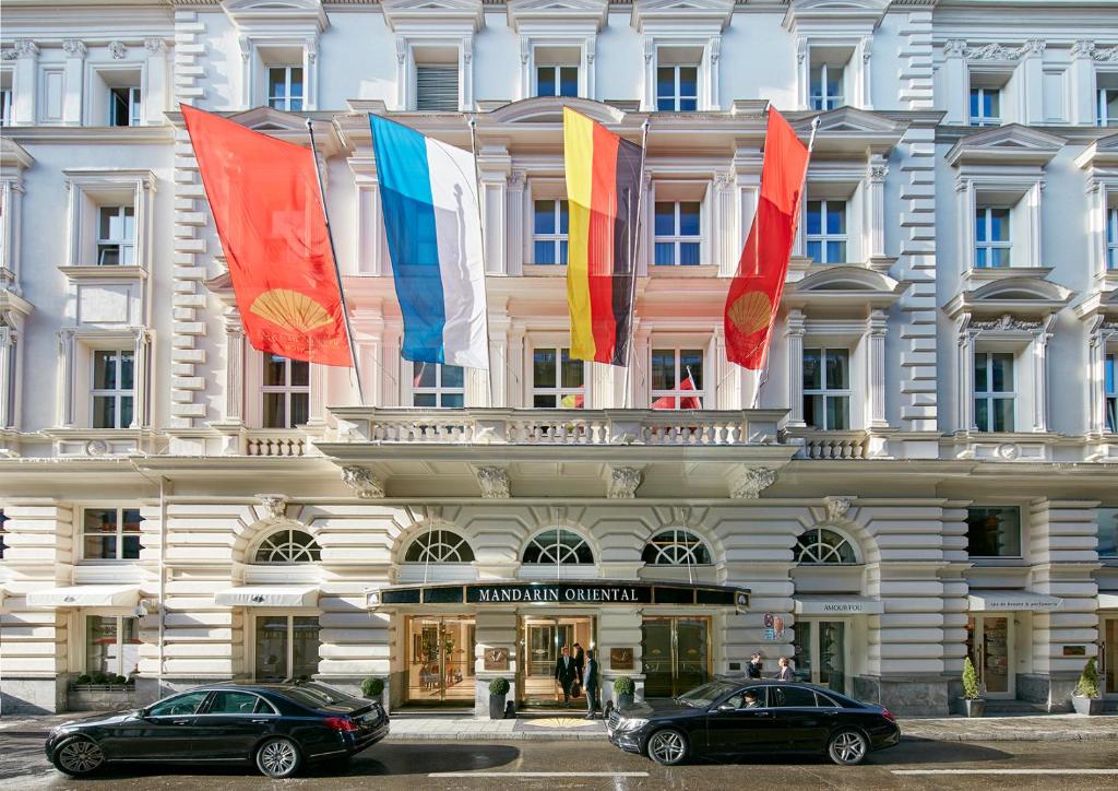 two cars parked in front of a building with flags at Mandarin Oriental, Munich in Munich