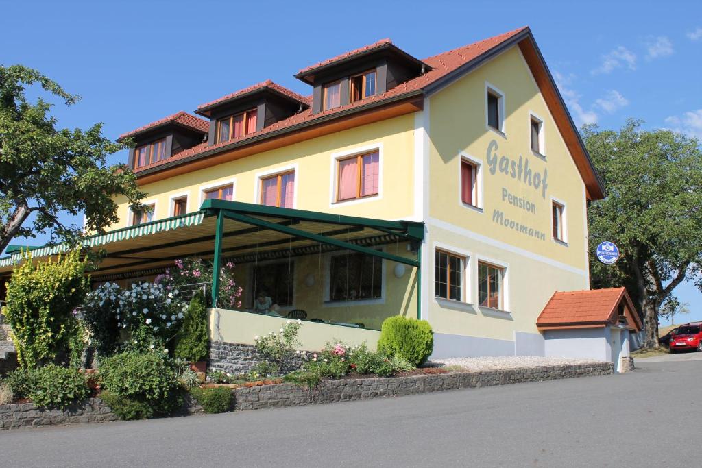 un edificio amarillo con un cartel en el costado en Gasthof zum Moosmann - Familie Pachernigg en Arnfels