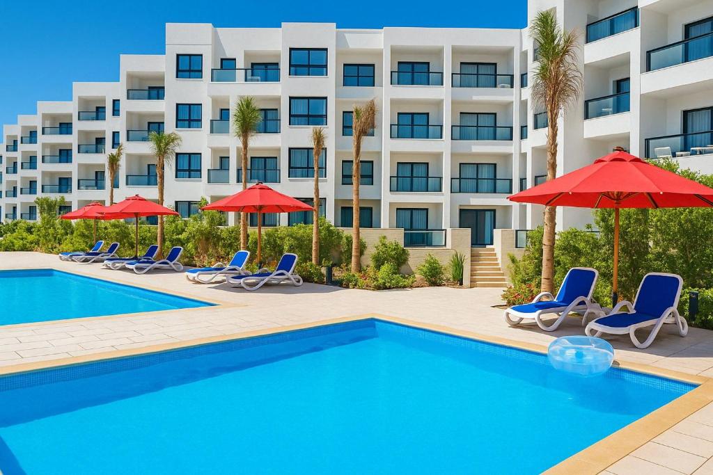 a pool with chairs and umbrellas in front of a hotel at Discover Tranquility by the Sea at Porto Said Resort in Port Said