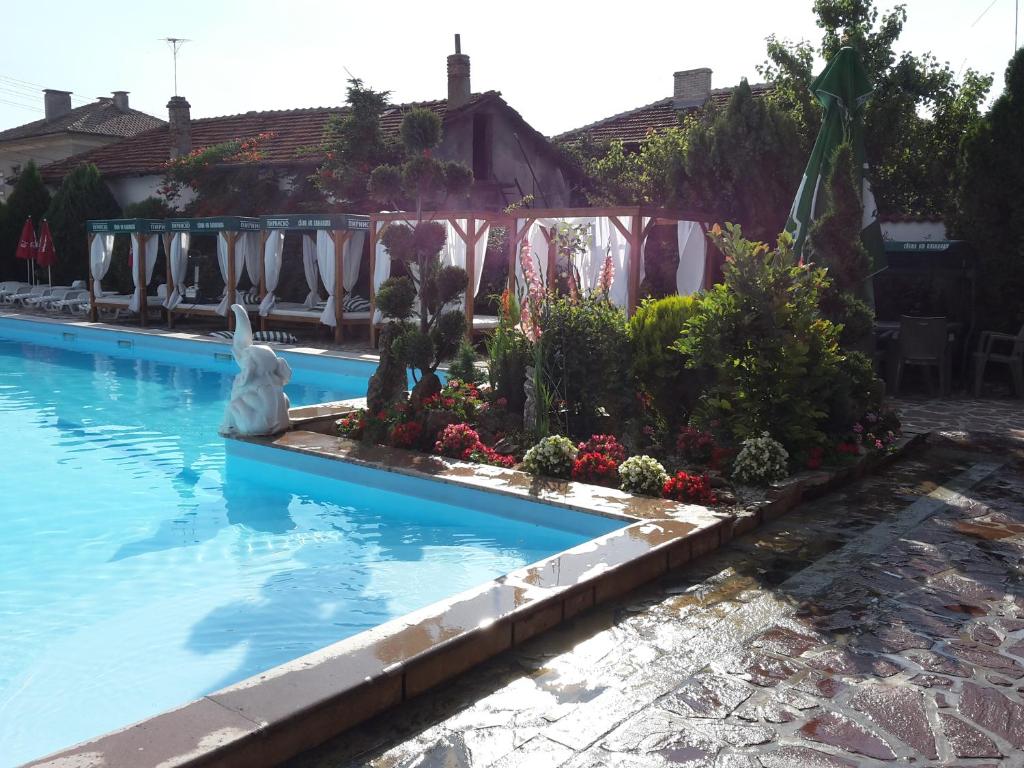 une piscine avec un jardin et une statue dans l'eau dans l'établissement Olympia, à Kharmanli